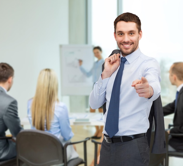 concept d'entreprise et de bureau - bel homme d'affaires avec une veste sur l'épaule pointant le doigt vers vous