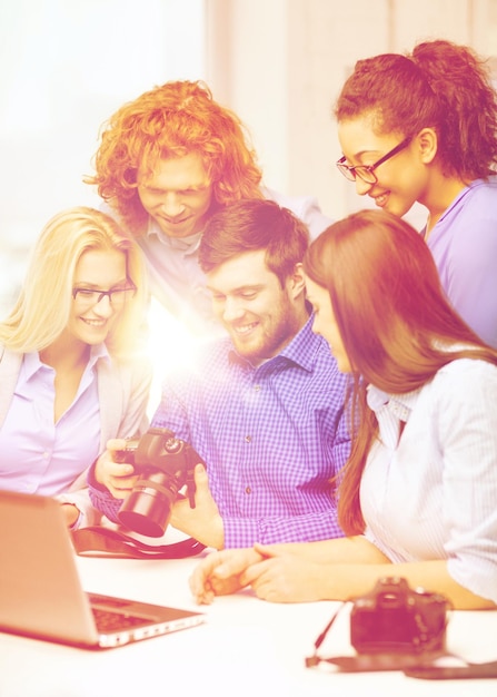 concept d'entreprise, de bureau et de démarrage - équipe créative souriante avec ordinateur portable et caméras photo travaillant au bureau