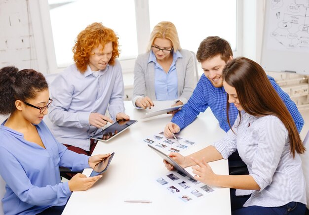 concept d'entreprise, de bureau et de démarrage - équipe créative souriante avec des ordinateurs de table et des papiers travaillant au bureau