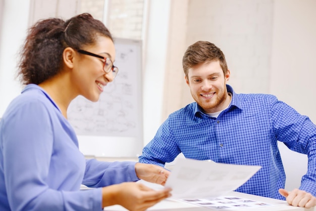 concept d'entreprise, de bureau et de démarrage - équipe créative souriante avec des papiers travaillant au bureau