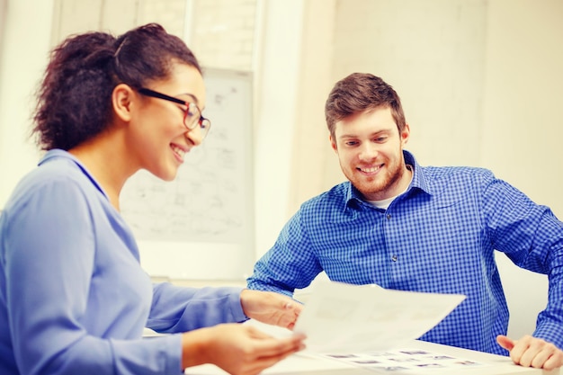 Photo concept d'entreprise, de bureau et de démarrage - équipe créative souriante avec des papiers travaillant au bureau