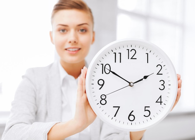 concept d'entreprise, de bureau, d'école et d'éducation - femme d'affaires attrayante montrant l'horloge