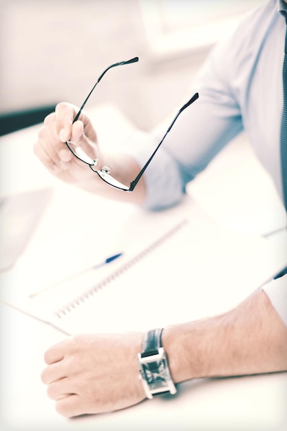 concept d'entreprise, de bureau, d'école et d'éducation - homme d'affaires avec des lunettes écrivant dans un cahier