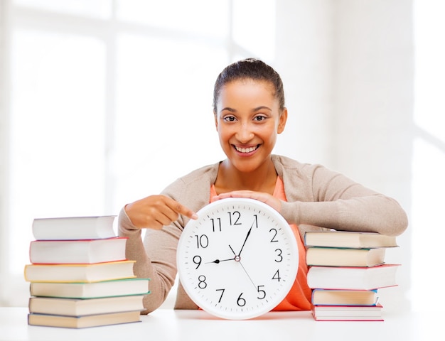 concept d'entreprise, de bureau, d'école et d'éducation - jolie femme montrant l'horloge