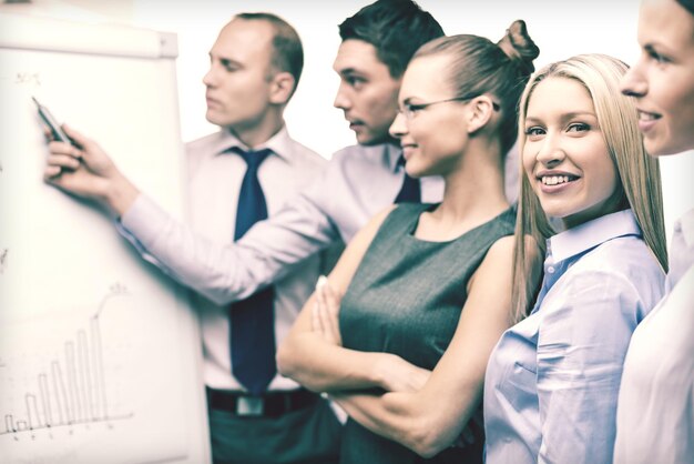 Concept D'entreprise Et De Bureau - équipe D'affaires Souriante Avec Des Graphiques Sur Un Tableau De Bord Ayant Une Discussion