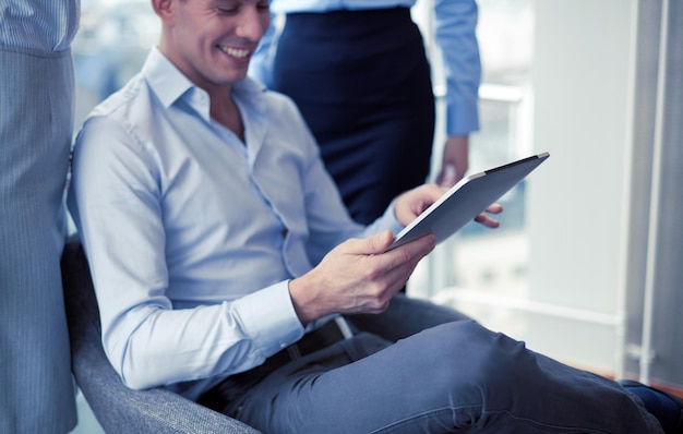 concept d'entreprise et de bureau - équipe d'affaires souriante travaillant avec une tablette au bureau