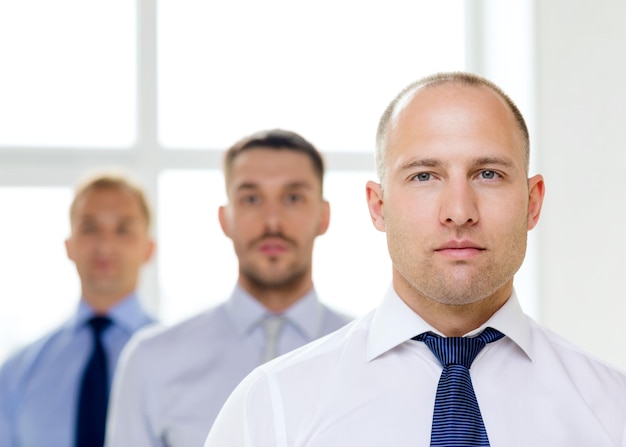 concept d'entreprise et de bureau - homme d'affaires sérieux au bureau avec équipe à l'arrière