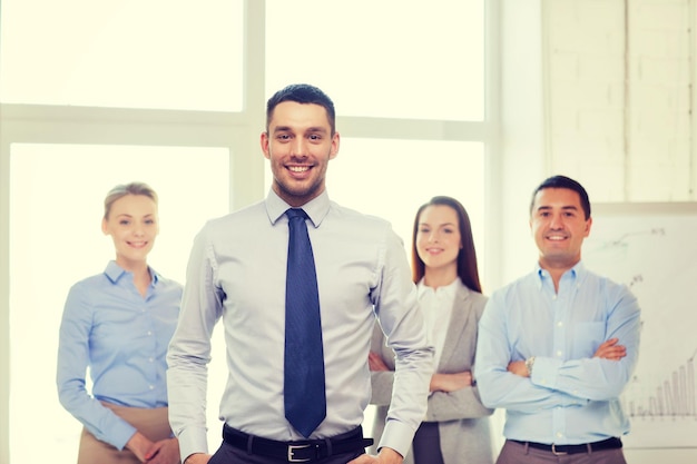 Concept d'entreprise et de bureau - souriant bel homme d'affaires avec l'équipe au bureau