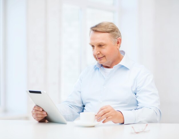 concept d'entreprise, de bureau, de vieillesse, d'école et d'éducation - vieil homme portant des lunettes avec un ordinateur tablette à la maison