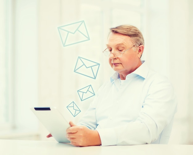 Photo concept d'entreprise, de bureau, de vieillesse, d'école et d'éducation - vieil homme portant des lunettes avec une tablette à la maison