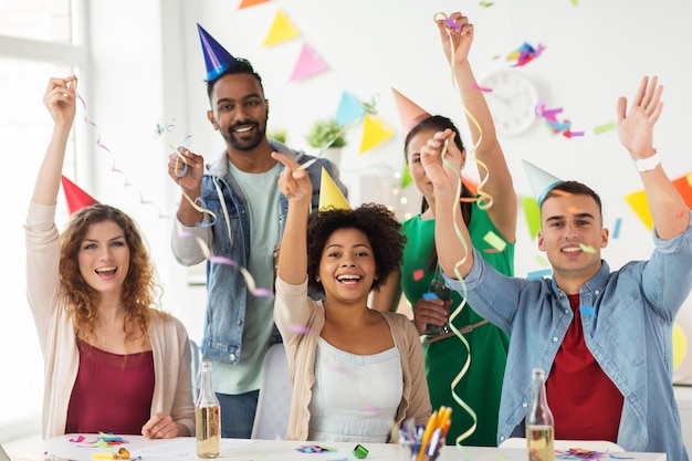 Photo concept d'entreprise, de célébration et de vacances - équipe heureuse avec des confettis et des serpentines s'amusant à la fête d'anniversaire au bureau