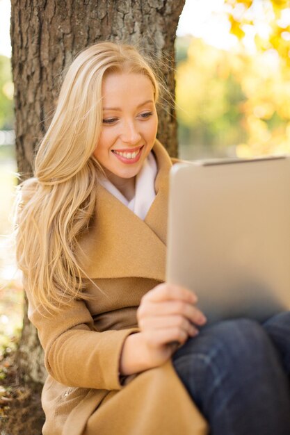 concept d'entreprise, de communication, de technologie moderne et de loisirs - femme avec tablet pc dans le parc d'automne