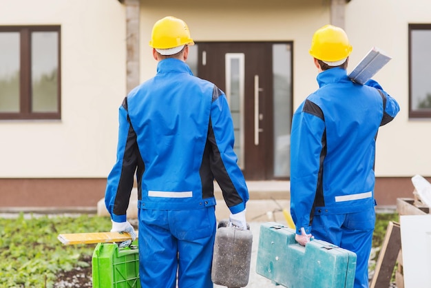 concept d'entreprise, de construction, de travail d'équipe et de personnes - groupe de constructeurs dans des casques avec des boîtes à outils à l'extérieur