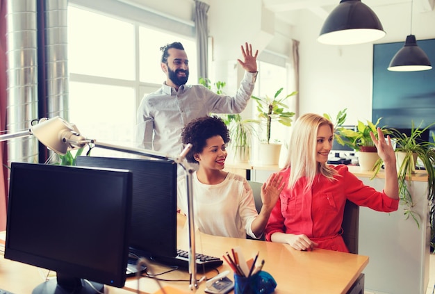 concept d'entreprise, de démarrage et de bureau - équipe créative heureuse agitant les mains au bureau