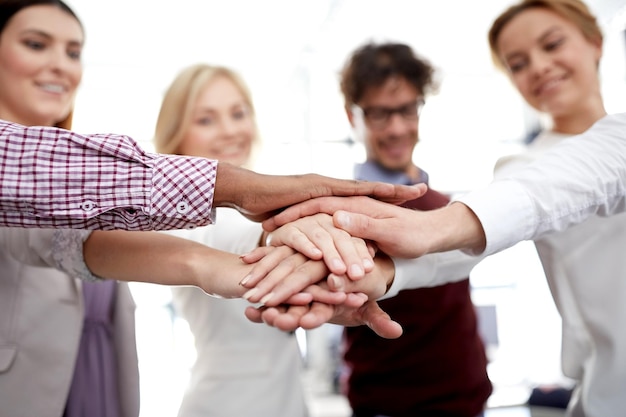 concept d'entreprise, de démarrage, de geste, de personnes et de travail d'équipe - équipe créative heureuse avec les mains les unes sur les autres au bureau