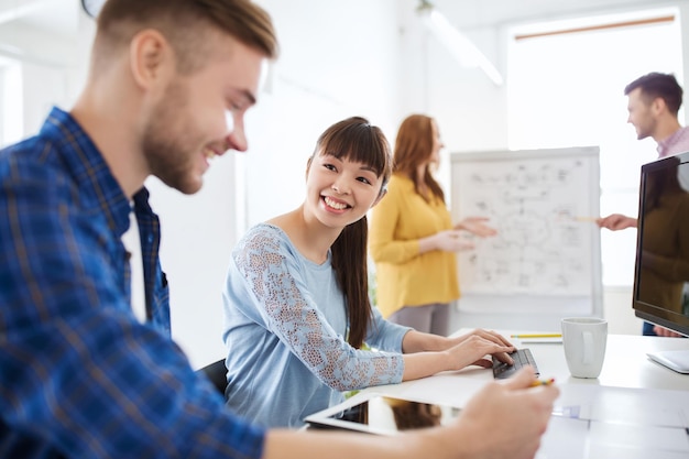 concept d'entreprise, de démarrage et de personnes - équipe créative heureuse avec ordinateur tablette pc au bureau