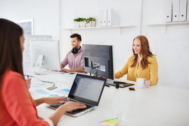 concept d'entreprise, de démarrage et de personnes - équipe créative heureuse avec des ordinateurs travaillant au bureau