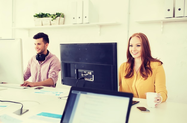 concept d'entreprise, de démarrage et de personnes - équipe créative heureuse avec des ordinateurs travaillant au bureau