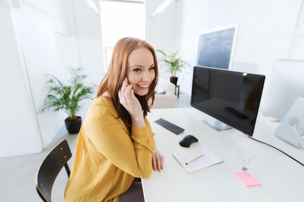 concept d'entreprise, de démarrage et de personnes - femme d'affaires heureuse ou travailleur créatif appelant sur smartphone au bureau