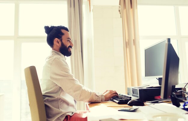 Concept d'entreprise, de démarrage et de personnes - homme d'affaires heureux ou employé de bureau masculin créatif avec ordinateur