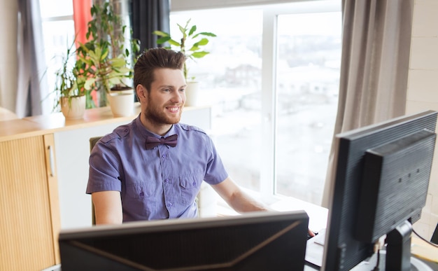 Concept d'entreprise, de démarrage et de personnes - homme d'affaires heureux ou employé de bureau masculin créatif avec ordinateur