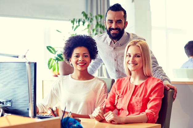 concept d'entreprise, de démarrage et de personnes - mise en réseau d'une équipe créative heureuse avec un ordinateur au bureau