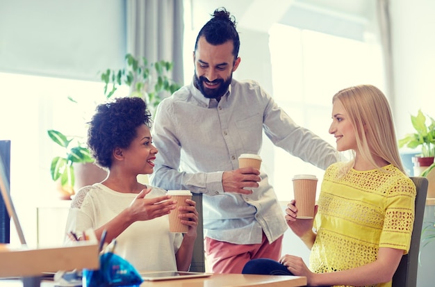 Photo concept d'entreprise, de démarrage, de personnes et de travail d'équipe - équipe créative heureuse buvant du café au bureau