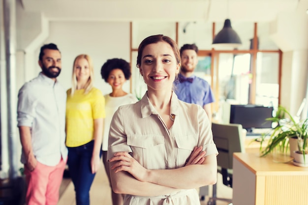 concept d'entreprise, de démarrage, de personnes et de travail d'équipe - jeune femme heureuse sur l'équipe créative au bureau