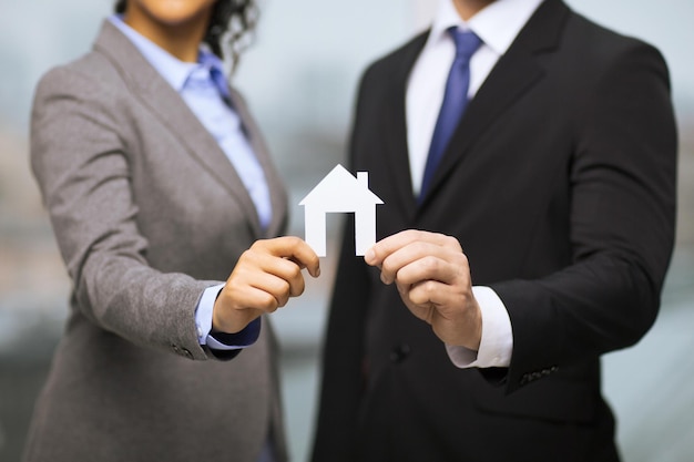 concept d'entreprise, d'éco, d'immobilier et de bureau - homme d'affaires et femme d'affaires tenant une maison de papier blanc au bureau