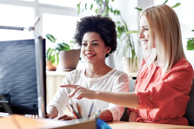 Photo concept d'entreprise, d'éducation, de démarrage et de personnes - femmes ou étudiants heureux avec ordinateur au bureau