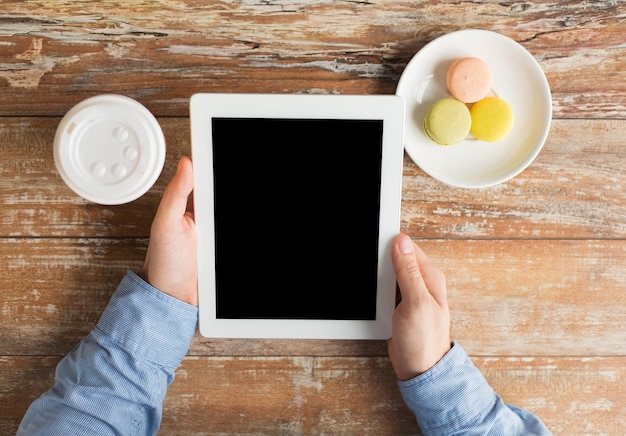 concept d'entreprise, d'éducation, de personnes et de technologie - gros plan sur des mains masculines avec un ordinateur tablette, des biscuits et une tasse de café sur la table