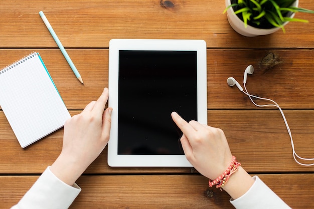 concept d'entreprise, d'éducation, de technologie, de personnes et de publicité - gros plan d'une femme avec un écran d'ordinateur tablette vierge sur une table en bois