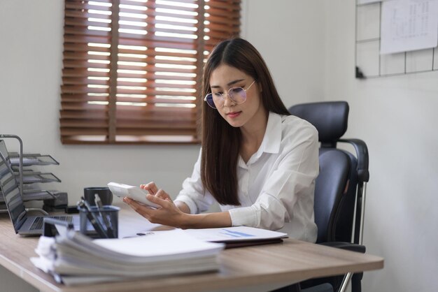 Concept d'entreprise Femme d'affaires lisant un document et utilisant une calculatrice pour calculer le budget d'investissement