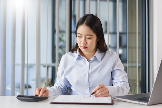 Concept d'entreprise Femme d'affaires lisant des données financières sur un document et calculant le coût du projet