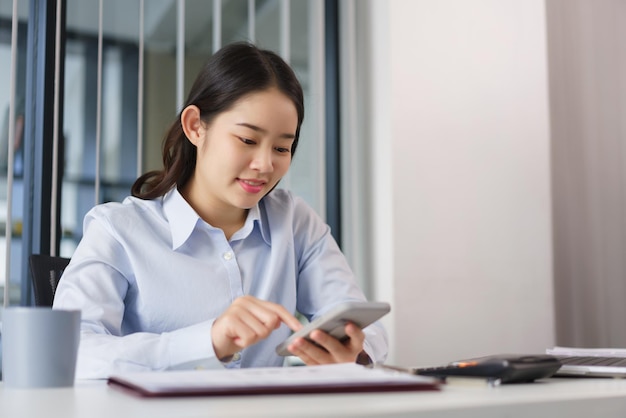 Concept d'entreprise Femme d'affaires vérifiant les données marketing sur smartphone pour analyser le coût du projet