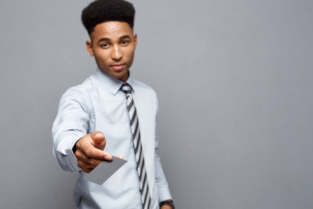 Concept d'entreprise - heureux bel homme d'affaires afro-américain professionnel donnant la carte de visite au client.