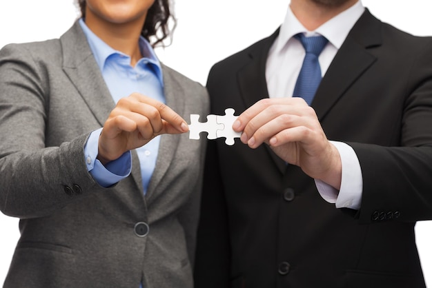 concept d'entreprise - homme d'affaires et femme d'affaires tenant des pièces de puzzle au bureau