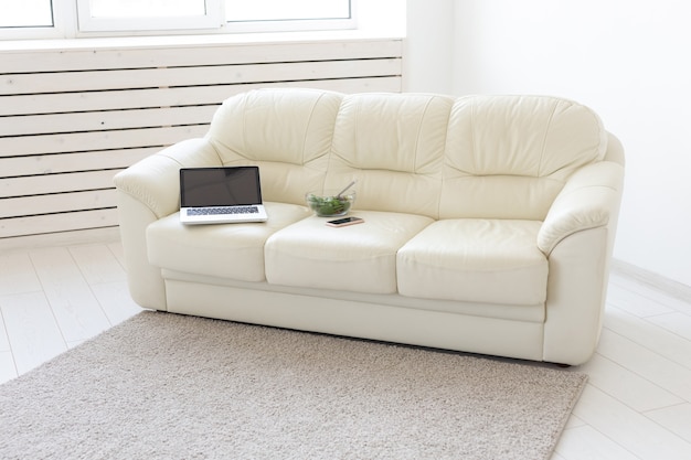 Concept d'entreprise et d'intérieur - vue d'un salon blanc avec canapé, un ordinateur portable ouvert, accueil