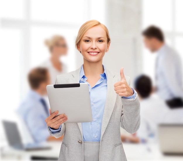 concept d'entreprise, d'internet et de technologie - femme souriante avec un ordinateur tablette montrant les pouces vers le haut au bureau