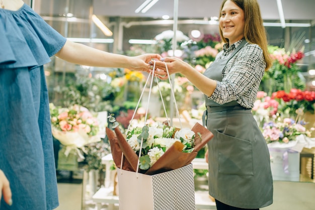 Concept d'entreprise de magasin de fleurs, fleuriste en tablier et cliente en boutique florale.