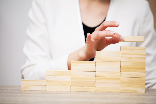 Concept d'entreprise, les mains de la femme composent des cubes en bois symbolisant le succès de l'entreprise