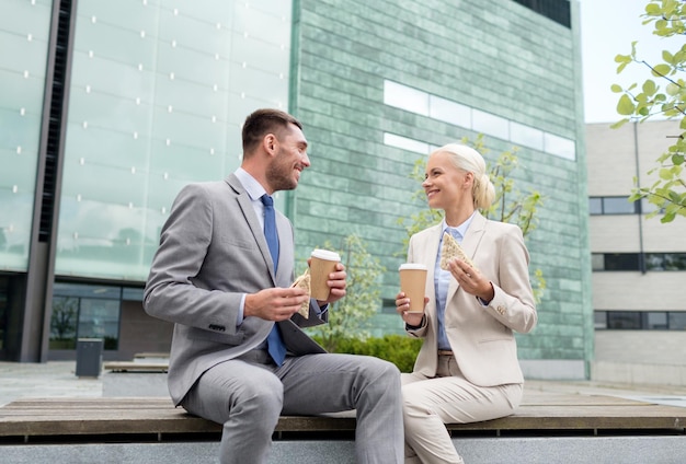 concept d'entreprise, de partenariat, de nourriture, de boissons et de personnes - hommes d'affaires souriants avec des gobelets en papier debout au-dessus d'un immeuble de bureaux