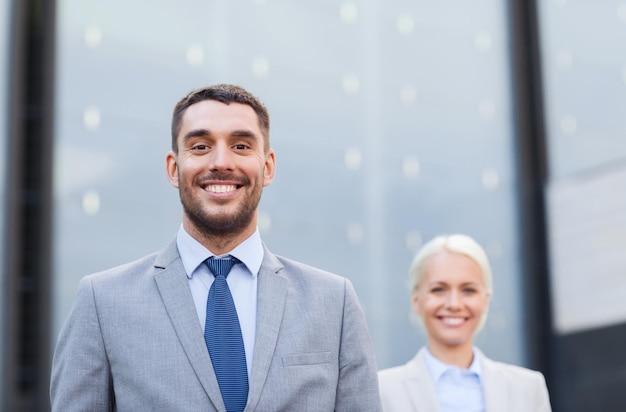 concept d'entreprise, de partenariat, de succès et de personnes - gros plan d'un homme d'affaires et d'une femme d'affaires souriants debout au-dessus d'un immeuble de bureaux