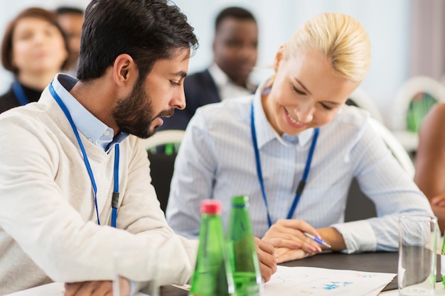 concept d'entreprise, de personnes et d'éducation - homme d'affaires et femme d'affaires lors d'une conférence internationale discutant de documents