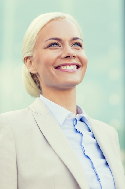 concept d'entreprise, de personnes et d'éducation - jeune femme d'affaires souriante sur un immeuble de bureaux