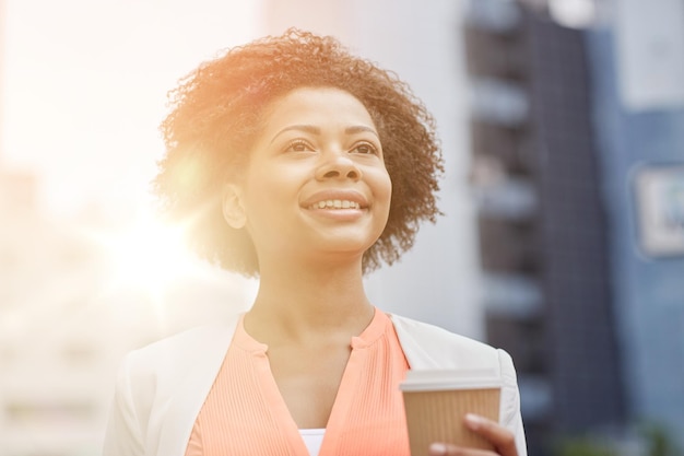 concept d'entreprise et de personnes - jeune femme d'affaires afro-américaine souriante avec une tasse de café en ville