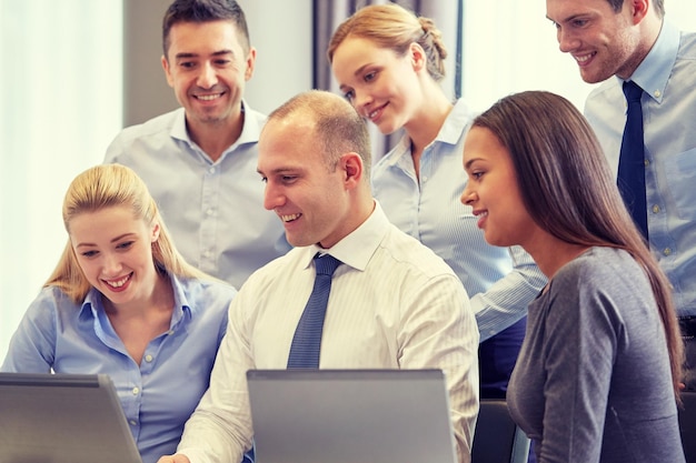 concept d'entreprise, de personnes et de technologie - équipe commerciale souriante avec réunion d'ordinateur portable au bureau