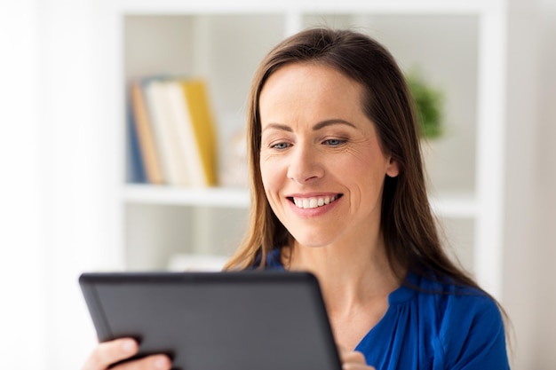 concept d'entreprise, de personnes et de technologie - femme souriante heureuse dans des verres avec un ordinateur tablette travaillant à la maison ou au bureau