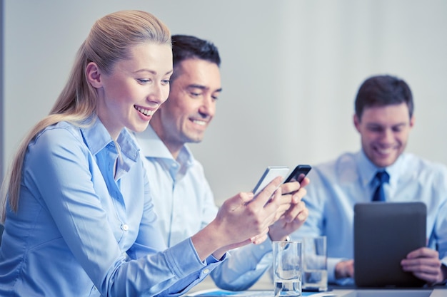 concept d'entreprise, de personnes, de technologie et de travail d'équipe - hommes d'affaires souriants avec smartphones et tablette pc réunion au bureau