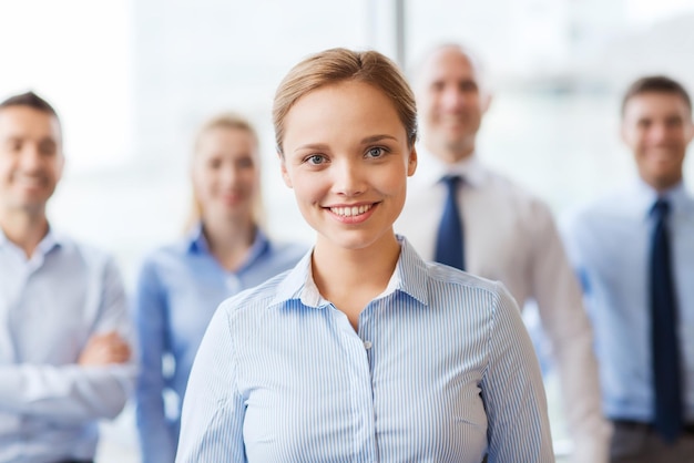 concept d'entreprise, de personnes et de travail d'équipe - femme d'affaires souriante avec un groupe d'hommes d'affaires au bureau